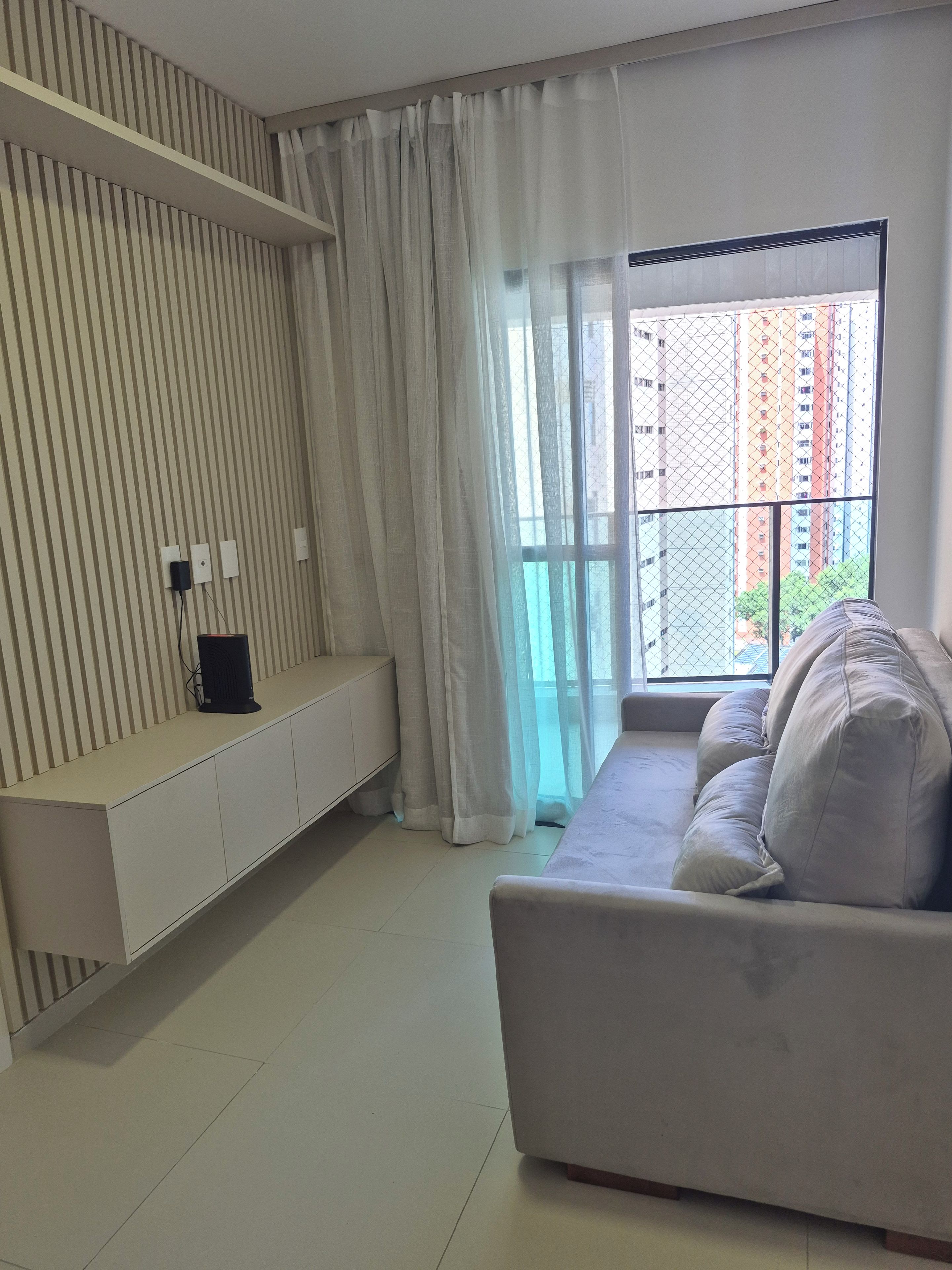 A modern living room with a sofa, a white console table, and a large window with curtains.