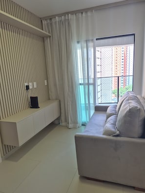 A modern living room with a sofa, a white console table, and a large window with curtains. - New Listing (Recife)