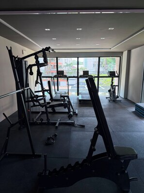 A gym with various exercise equipment, large windows, and a view of buildings outside. - New Listing (Recife)