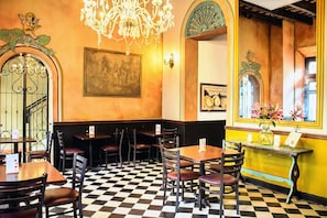 A restaurant interior with checkered flooring, wooden tables and chairs, a chandelier, and decorative wall elements. - Patio Elba Old San Juan (San Juan)