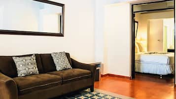 A room with a brown sofa, patterned cushions, a mirror, and a patterned rug.