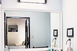 Un baño con un espejo grande, un perchero y un certificado enmarcado en la pared.