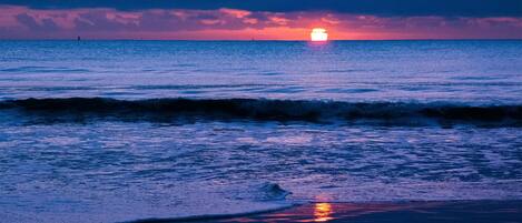 A beach scene with waves and a sunset.