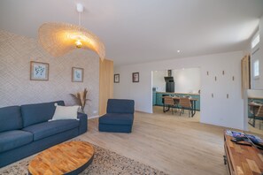 Una sala moderna con sofá, sillón y una mesa de centro, que da a una zona de cocina.