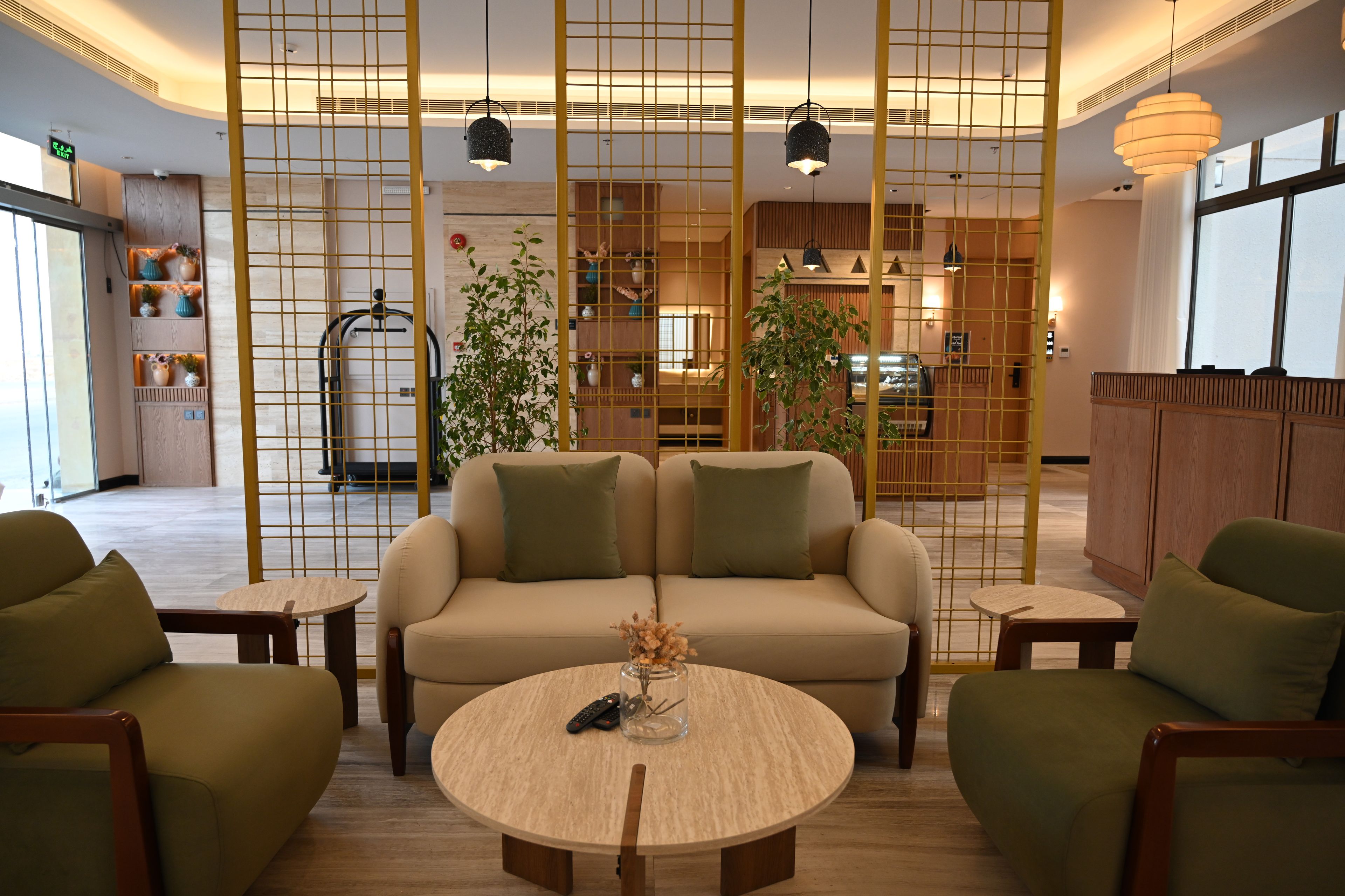 Un lobby moderno con un sofá, sillas, una mesa redonda y plantas decorativas.