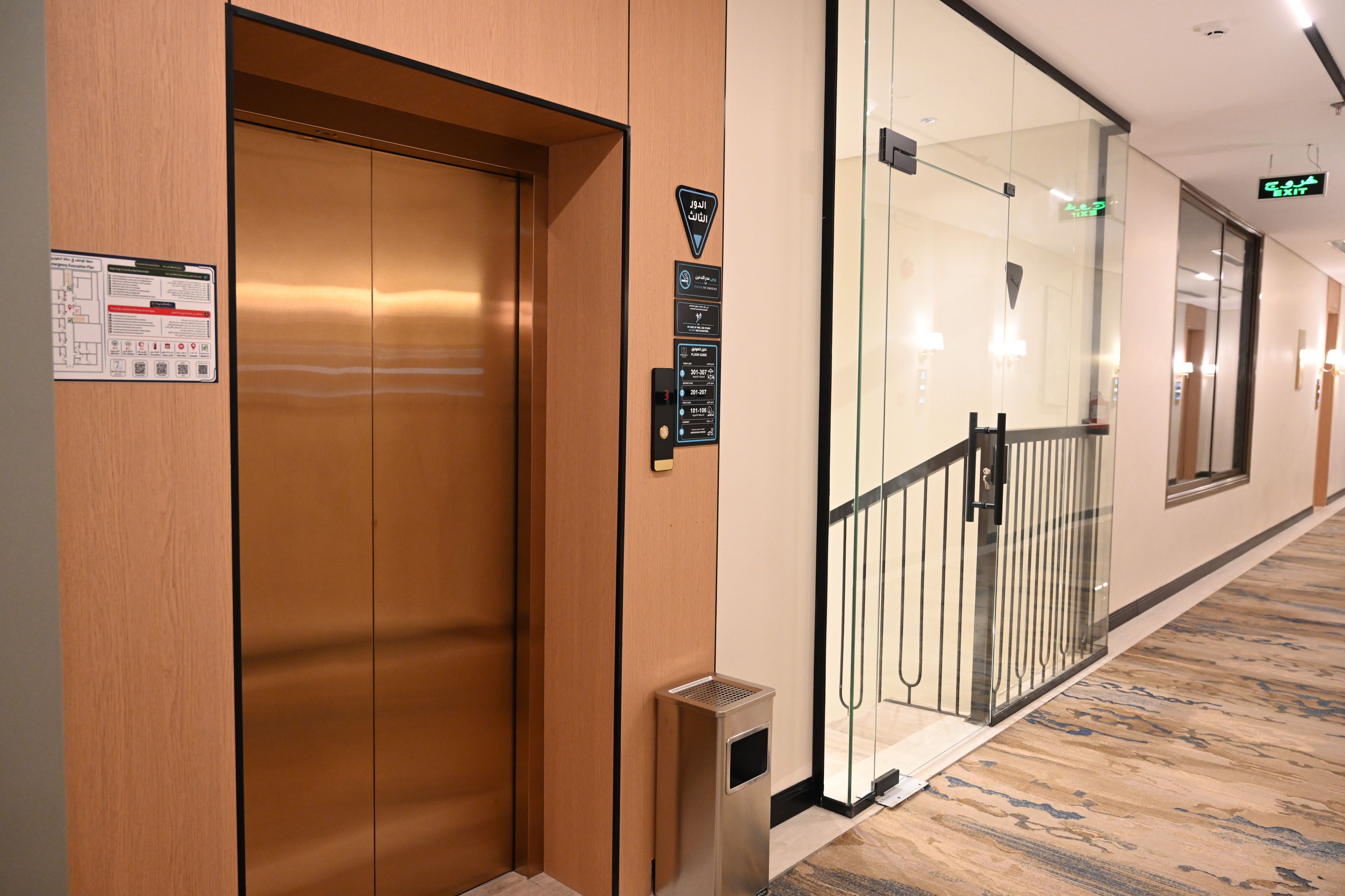 An elevator with emergency instructions and a glass door with a metal railing.
