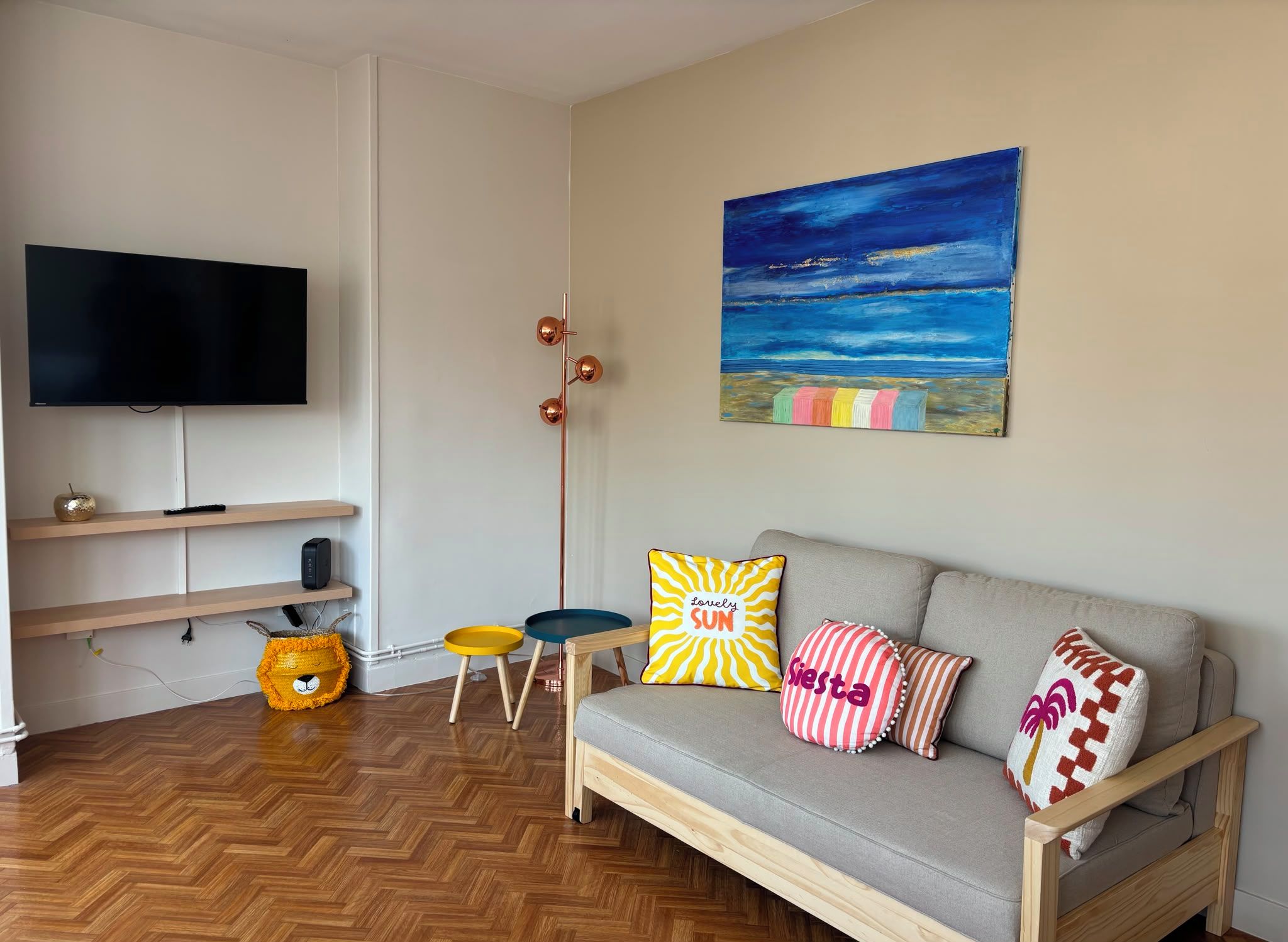 Un salon avec un canapé, un téléviseur, un tableau et un panier pour chien.