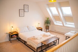A bedroom with a bed, bedside tables, a bench, a potted plant, and skylights. - 3-Bed House Sleeps 7 with Parking · Garden · Walk to Peel Park, Salford (Greater Manchester)