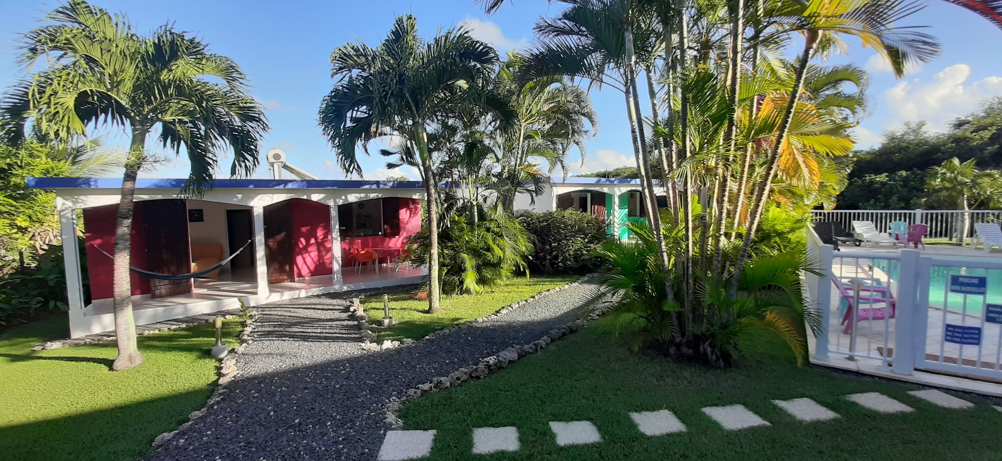 A resort with a covered outdoor seating area, a pool, and lush tropical vegetation.