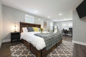 Une chambre à coucher comprenant un lit, une table de chevet, une lampe et un bureau avec une chaise.