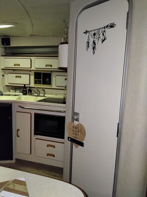 Una kitchenette compacta con microondas, horno y lavadero.