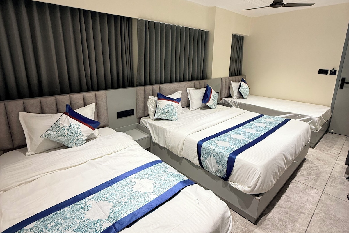 A hotel room with two beds, a ceiling fan, and a large window with curtains.