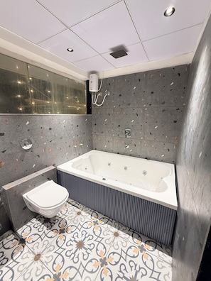 A modern bathroom with a freestanding bathtub, a toilet, and a vanity. - Hotel Pacific Comfort (Ahmedabad)