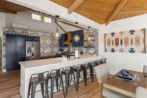 A modern kitchen with a central island, bar stools, pendant lighting, and patterned backsplash. - Sedona Red Rock Retreat for 8 | 2 Homes, 4BR, Sunroom Dining, Game Room, Fire Pit & Private Patios (Sedona)