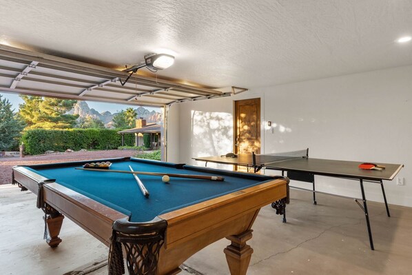 A pool table with a blue felt surface and a billiard cue in the foreground. - Sedona Red Rock Retreat for 8 | 2 Homes, 4BR, Sunroom Dining, Game Room, Fire Pit & Private Patios (Sedona)