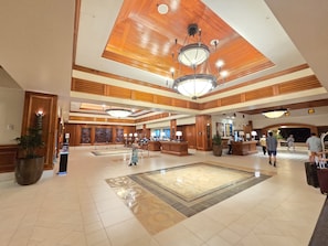 Eine geräumige Lobby mit hoher Decke, mehreren Rezeptionstheken und einer großen Kronleuchter.