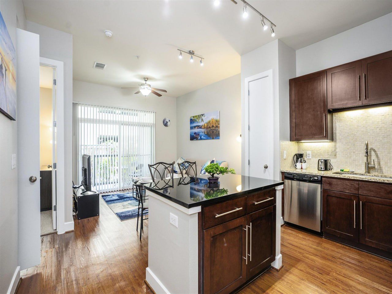 A modern kitchen with wooden cabinets, a black countertop, and a dishwasher.