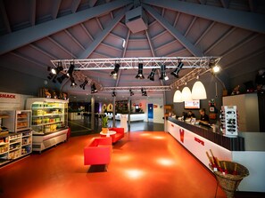 A spacious indoor area with a high ceiling, a reception desk, seating areas, and a snack machine. - Spacious Holiday Bungalow for 8 Guests (Biddinghuizen)