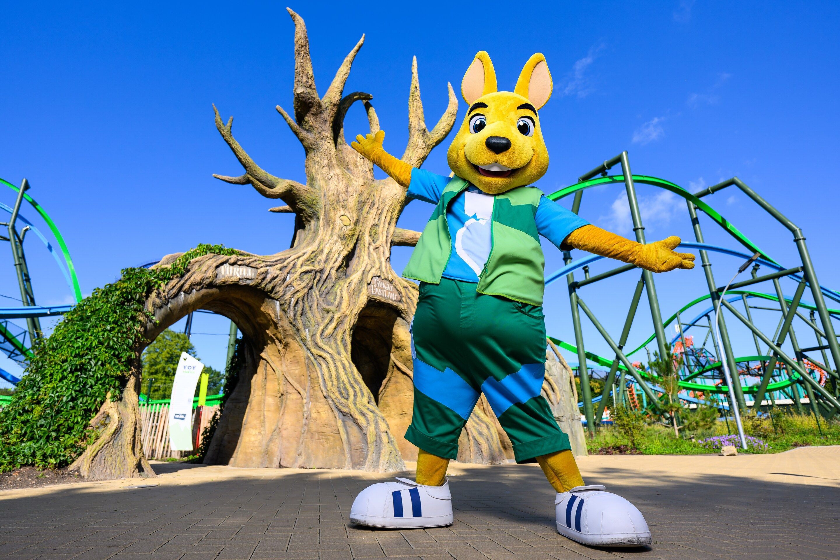 A mascot standing in front of a large tree structure.