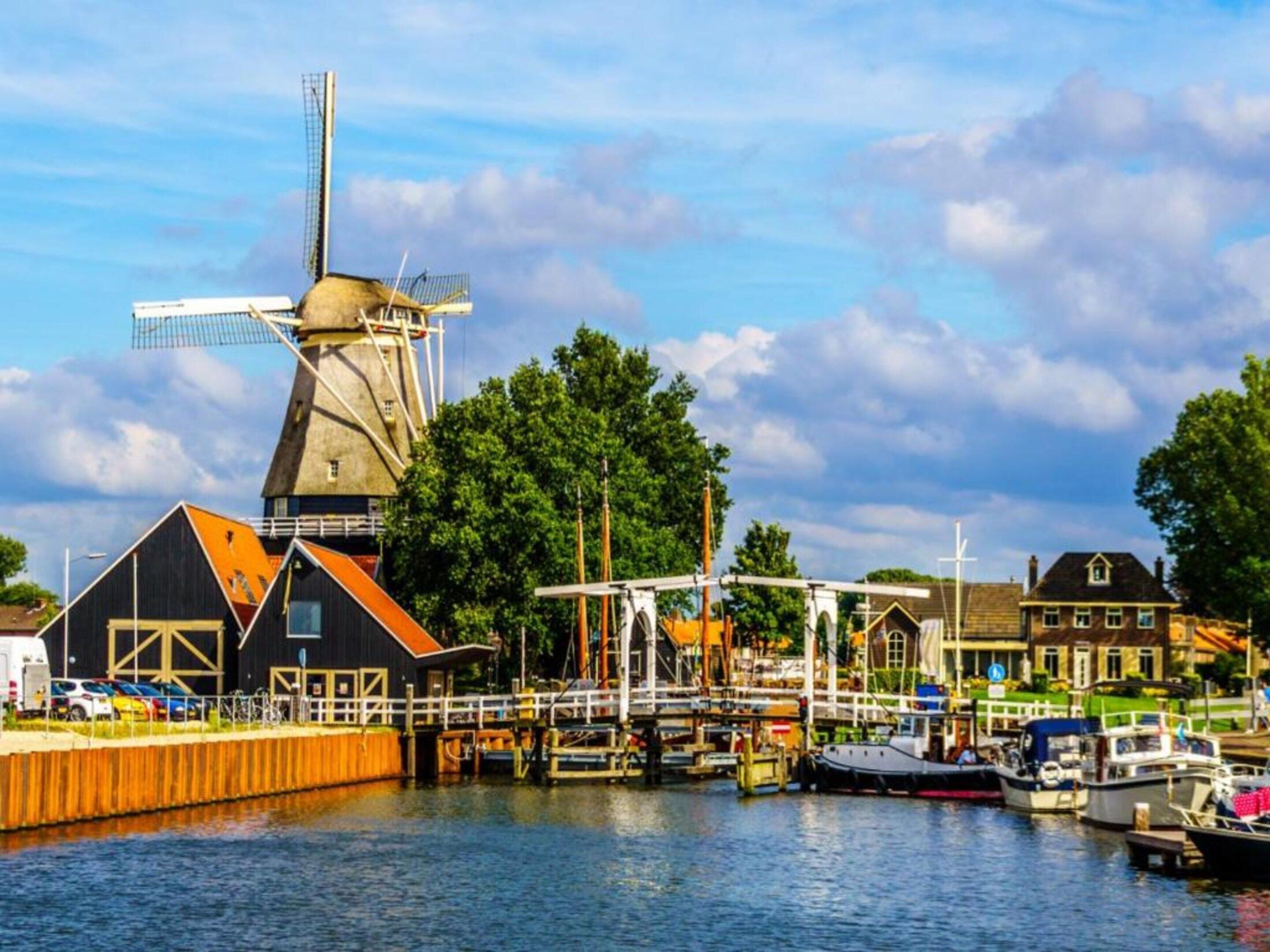 A windmill, a dock, and boats in a harbor.