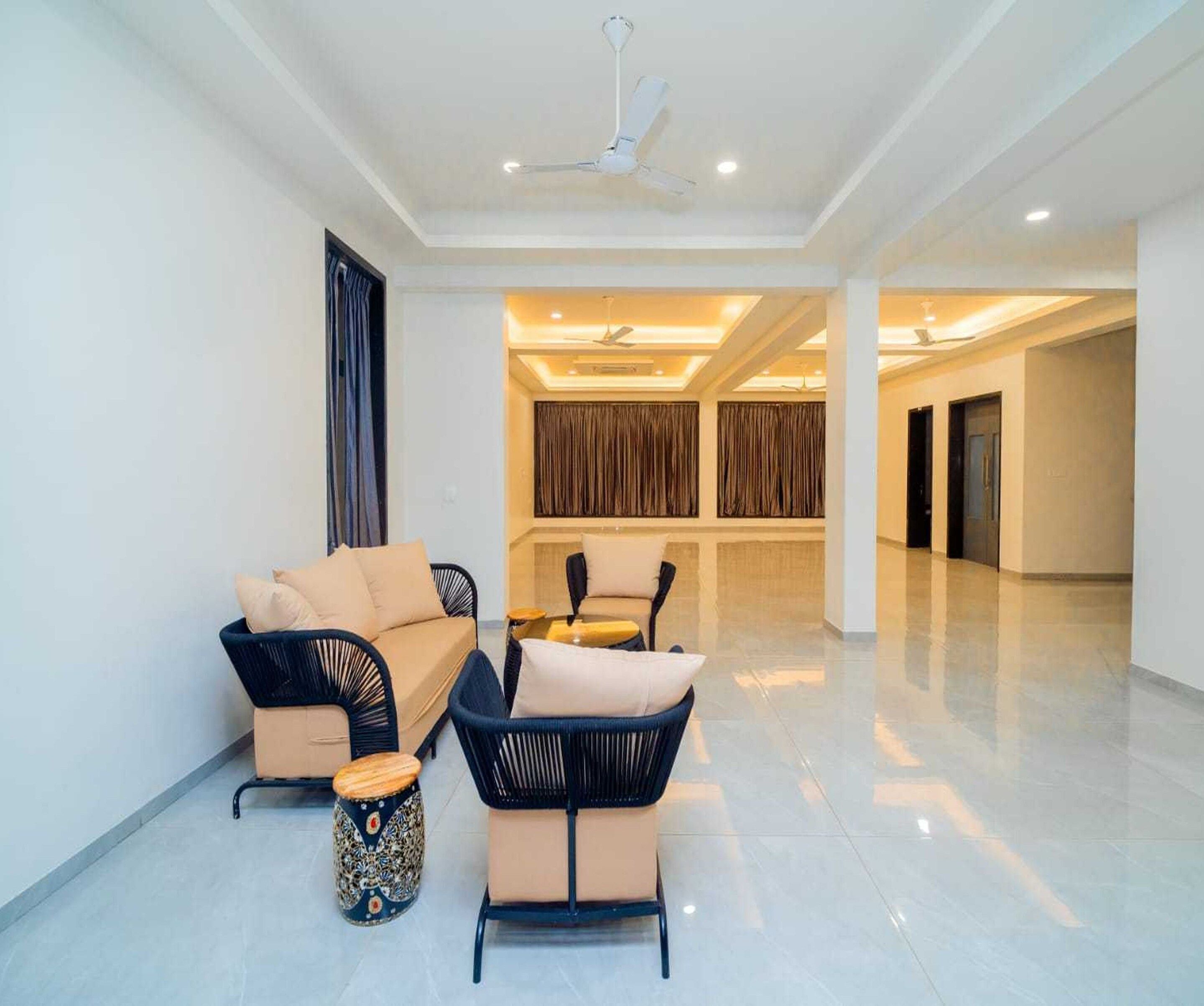 A spacious living area with a sofa, armchairs, and a decorative stool.