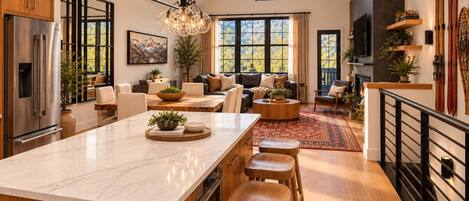 A spacious kitchen with a large island, wooden cabinets, and a modern chandelier.