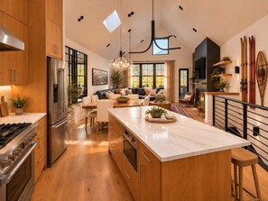 Cozinha moderna com uma ilha grande, eletrodomésticos de aço inoxidável e área de jantar com vista.