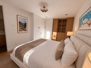 Quarto com cama, armário de madeira, um quadro e luminária.