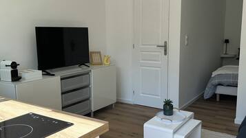 A modern living room with a flat-screen TV, a small white table, and a sofa.