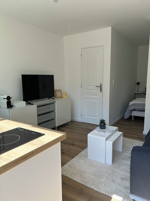 Een moderne woonkamer met een flatscreen televisie, een witte salontafel en een bank.