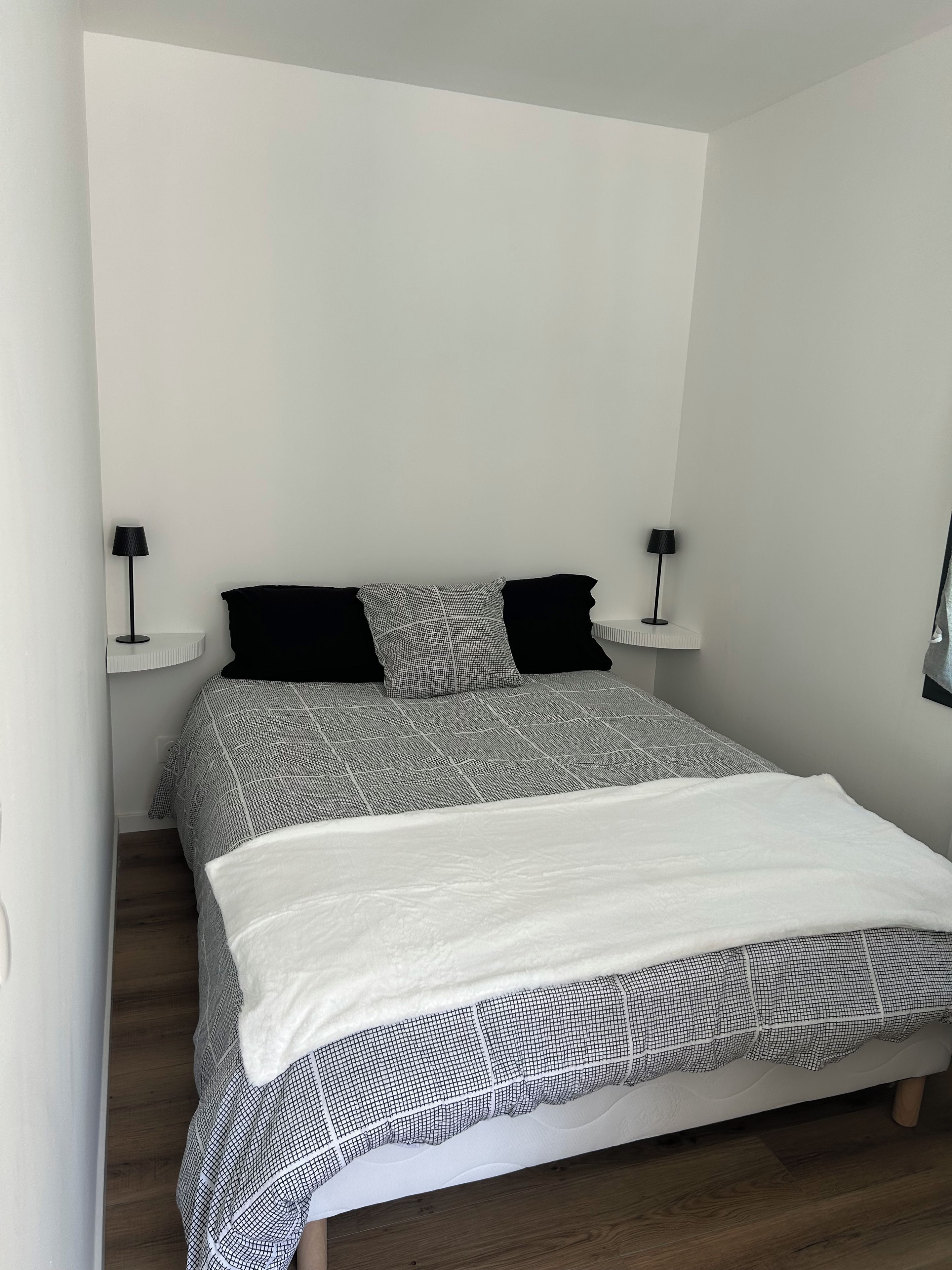 Een slaapkamer met een bed, twee bedlampen en een witte muur.