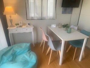 A room with a desk, a chair, a bean bag, a television, and a window with curtains.