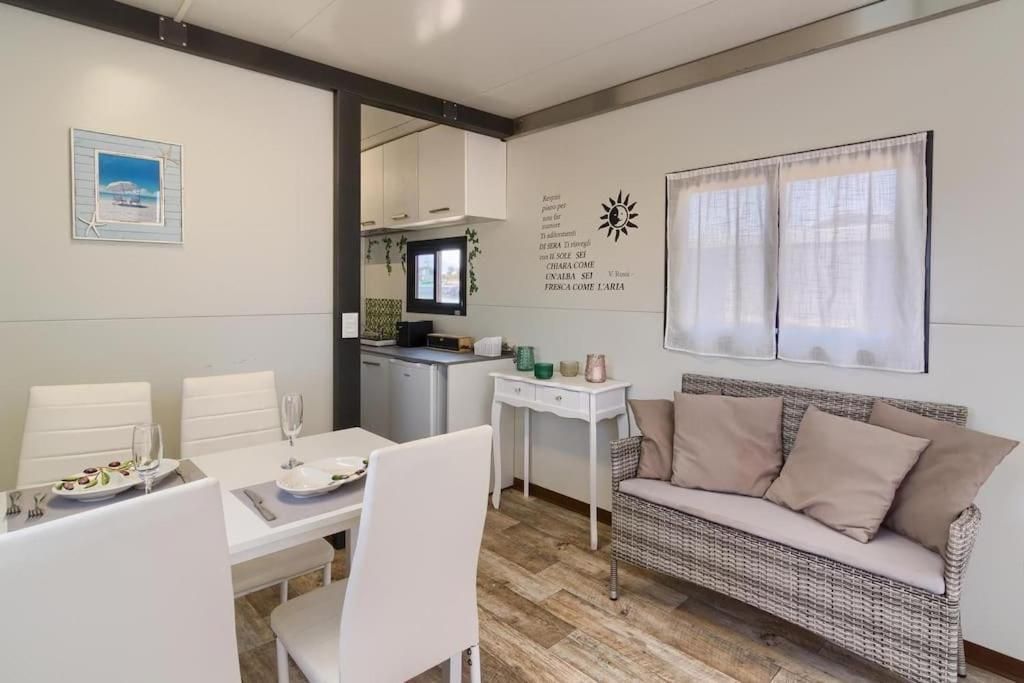 A dining area with a table set for two, a sofa, and a kitchen in the background.