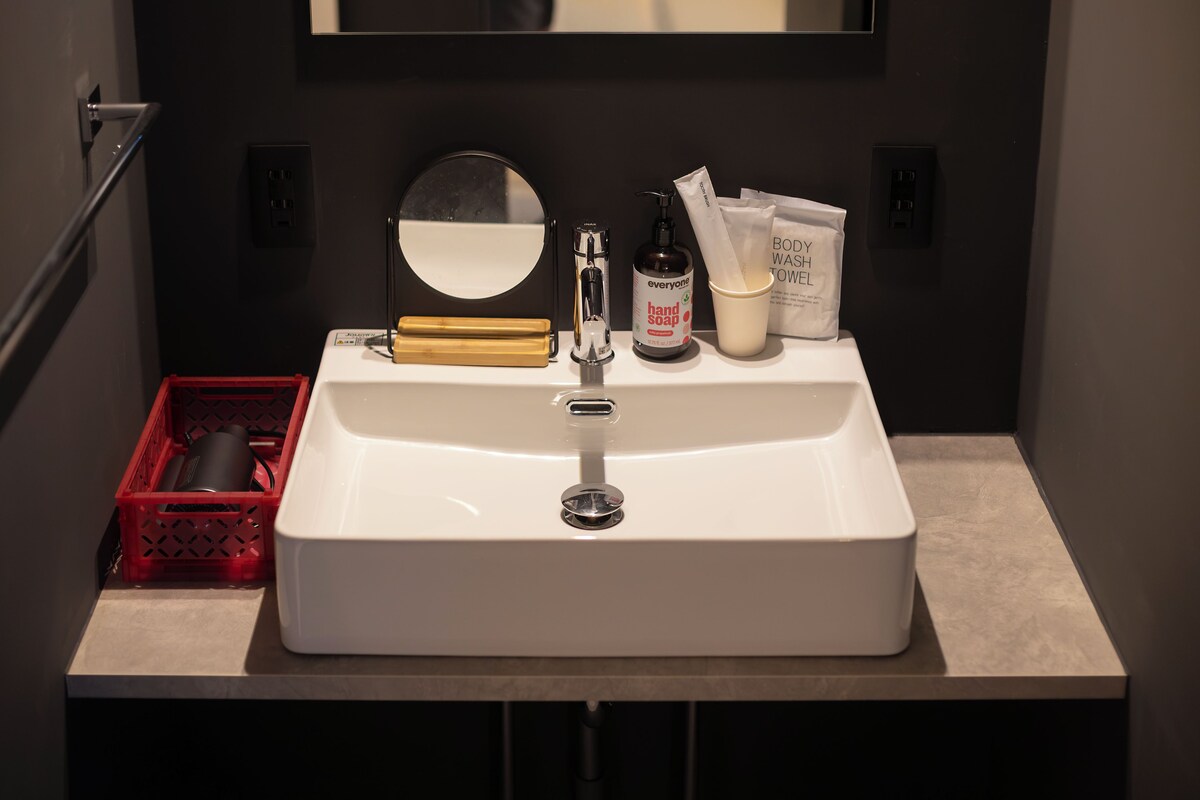A bathroom sink with a mirror, soap dispenser, and hand towel.