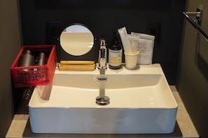 A bathroom sink with toiletries, a red basket, and a mirror. - BITO DISCONT HOTEL LDx (Tsuyama)