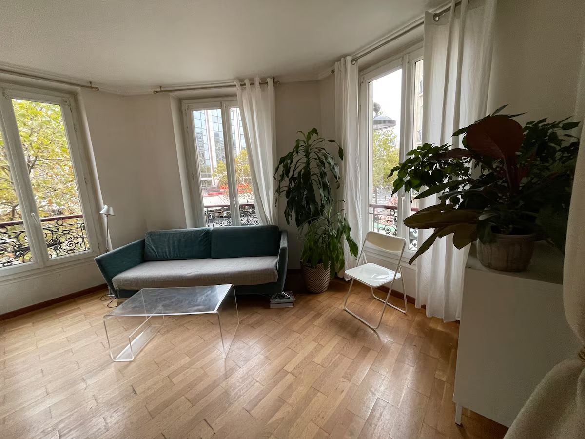 Una habitación con sofá, sillón, mesa y ventanas amplias.