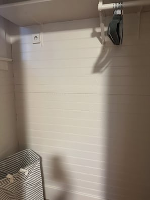 Et værelse med hvide panelvægge, en stribet pude og et håndklædetørrestativ.