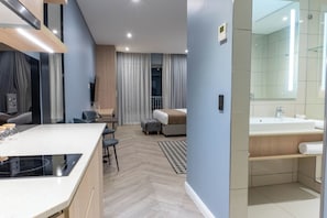 Une chambre d’hôtel moderne comprenant un coin cuisine, un coin salon, un lit et une salle de bain.