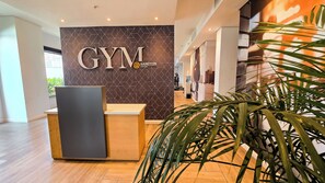 Un comptoir d’accueil avec, en arrière-plan, le logo de l’hôtel « GYM Sandton ».