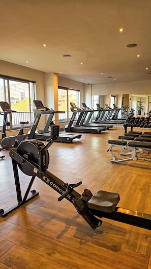 Une salle de sport équipée de plusieurs tapis de course, de vélos d’appartement et d’appareils de musculation.