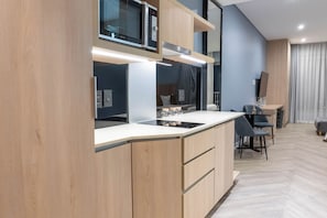 Une cuisine moderne dotée d’appareils électroménagers intégrés, un coin repas avec une table et des chaises, et une grande fenêtre agrémentée de rideaux.