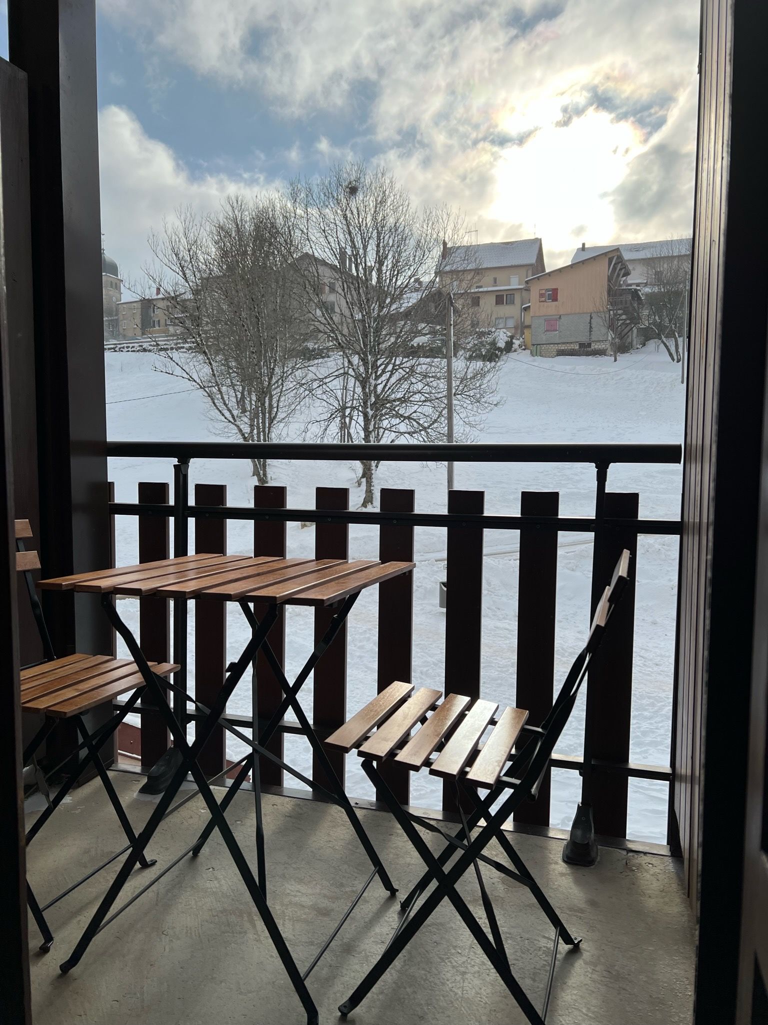 A balcony with wooden furniture and a view of a snowy landscape.