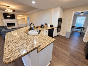 A modern kitchen with granite countertops, white cabinetry, a built-in oven, and a dining area with a bench. - Cozy, Clean, Home with lots of things to do, Great for Short or Long term stays (Montgomery)