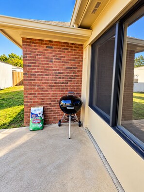 A patio area with a brick wall, a barbecue grill, and a bag of charcoal. - Cozy, Clean, Home with lots of things to do, Great for Short or Long term stays (Montgomery)