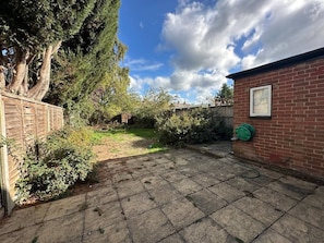 A paved backyard with a brick wall, a hose reel, and a framed picture. - 4 bedroom House in Guildford! (Surrey)