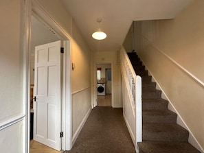 A hallway with carpeted stairs leading to a laundry room. - 4 bedroom House in Guildford! (Surrey)