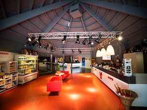 A spacious indoor area with a high ceiling, a reception desk, seating areas, and a snack machine. - Comfortable Stay Near Walibi Holland (Biddinghuizen)