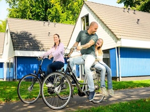 A family on a tandem bicycle in front of a residential building with a blue garage door. - Comfortable Stay Near Walibi Holland (Biddinghuizen)