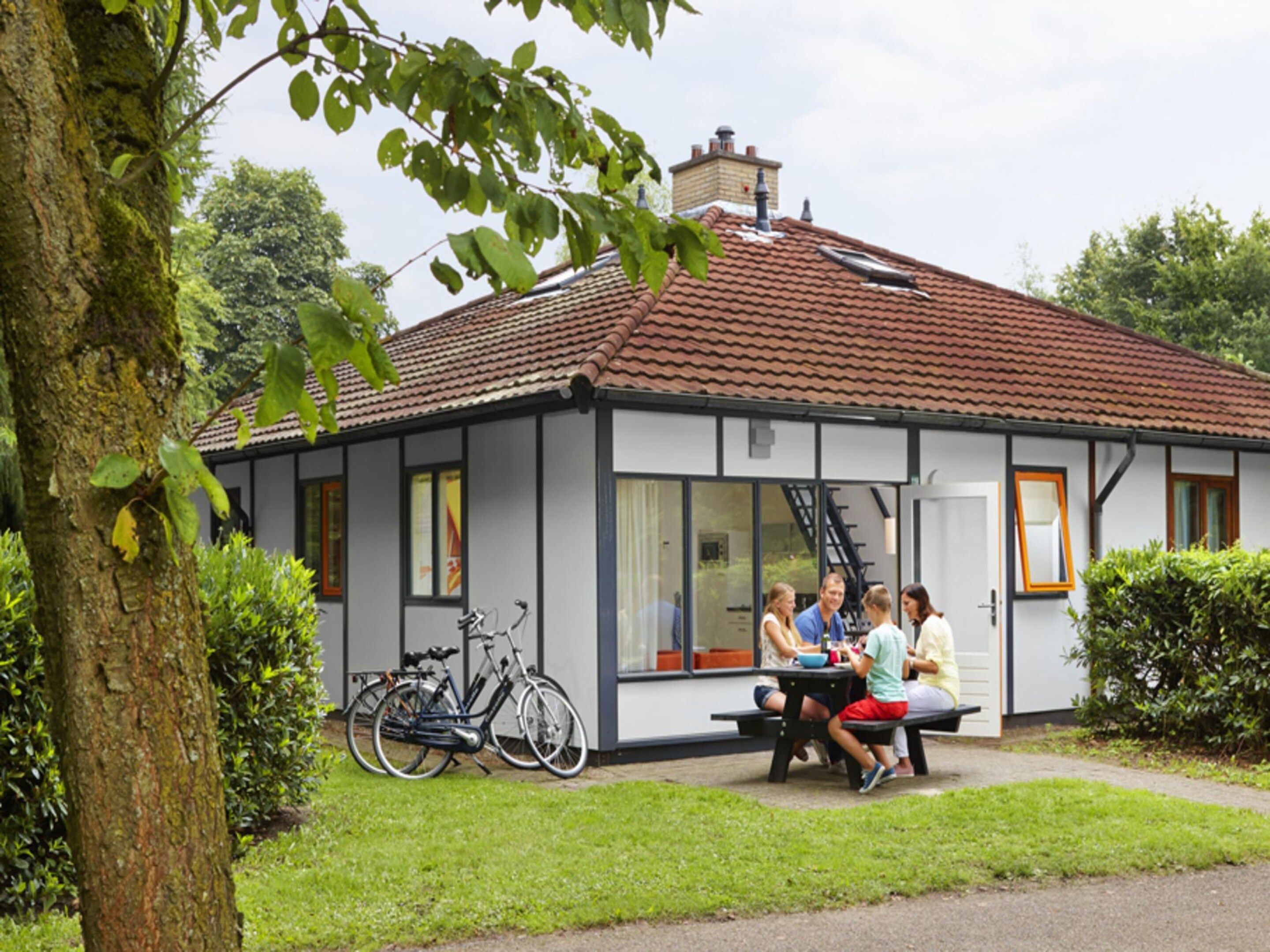 A small building with a tiled roof, a bench outside, and bicycles parked nearby.