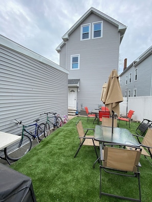 A backyard with a lawn, a table with chairs, and bicycles. - 3-BEDROOM, 2 FULL BATH, Central AC, Laundry & Parking - Downtown Elizabeth (Elizabeth)